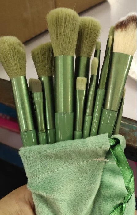 13Pcs green makeup brush set with soft bristles and matte handles, stored in a matching green velvet pouch for cosmetic use.